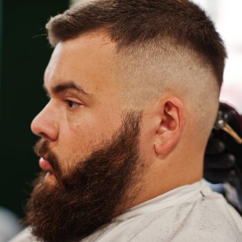 Handsome bearded man at the barbershop, barber at work.